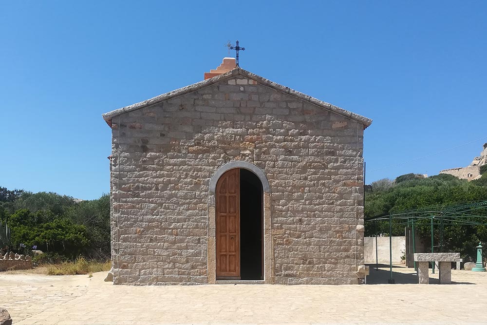 la piccola e piu antica chiesa, facciata in granito con portale in legno e tetto a capanna