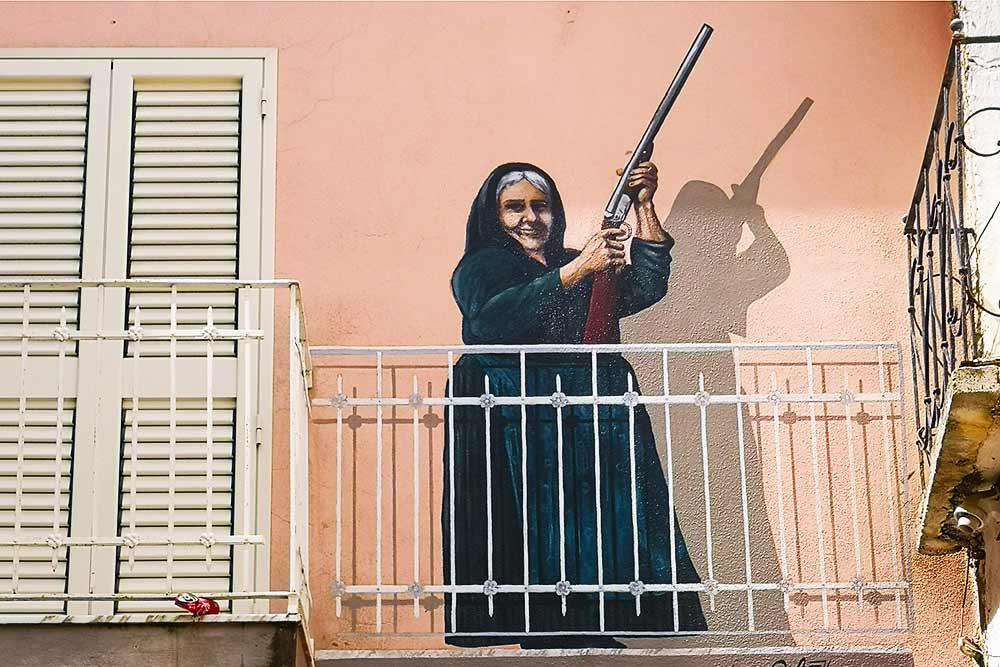 Murales di Orgosolo che raffigura una signora con il fucile in mano