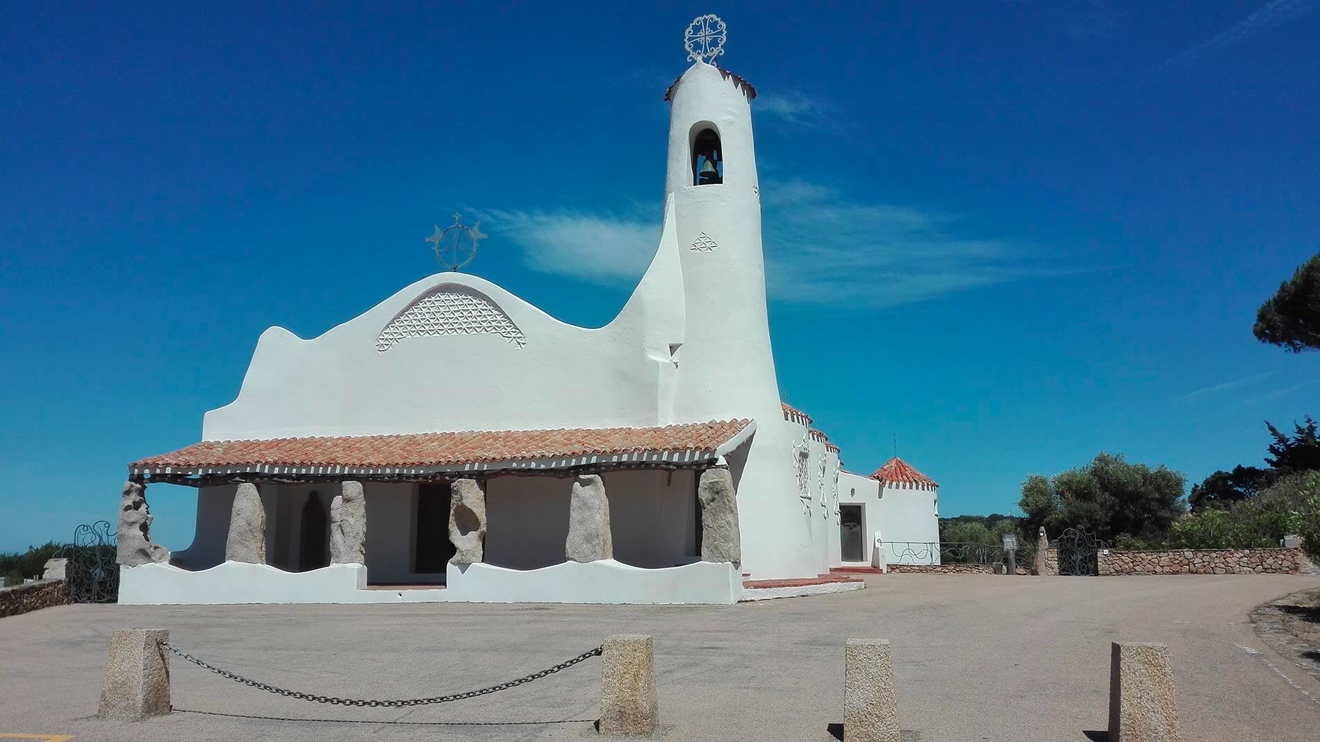 Costa-Smeralda-chiesa-Stella-Maris-(un-porticato-di-grandi-pietre-di-granito-precedono-il-bellissmo-portale-di-ottone-con-sulla-destra-il-campanile-a-cono