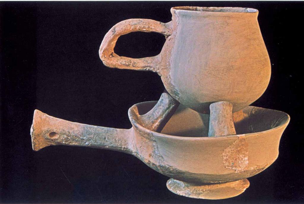 Utensili in ceramica. Sotto un "fornello" con manico lungo e tre listelli interni che reggono un "bollilatte" un olla panciuta con grosso manico.