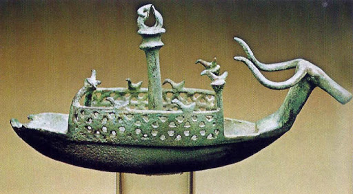 Navicella in bronzo con protome bovina e uccellini sopra a delle paratie forate.