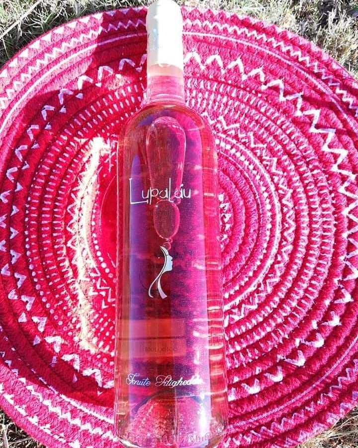 Sopra a un cestino sardo di colore fucsia, una bottiglia di vino rosato.