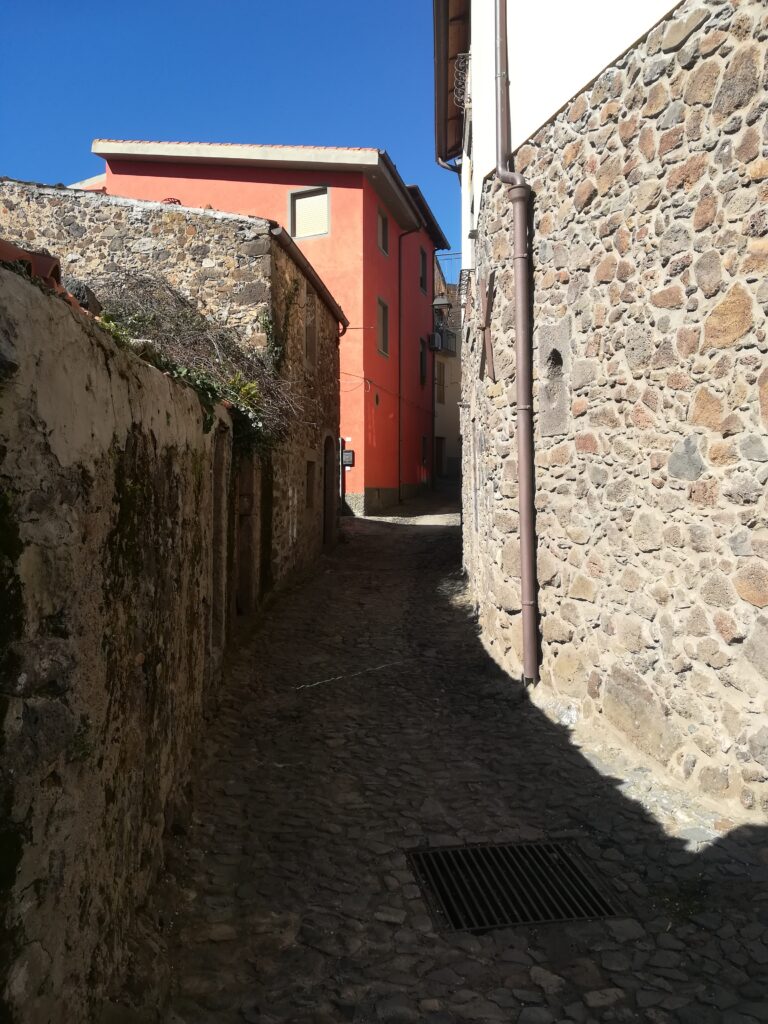 Uno stretto vicolo caratteristico del paese, case a destra e sinistra in pietra lavica compreso il selciato.