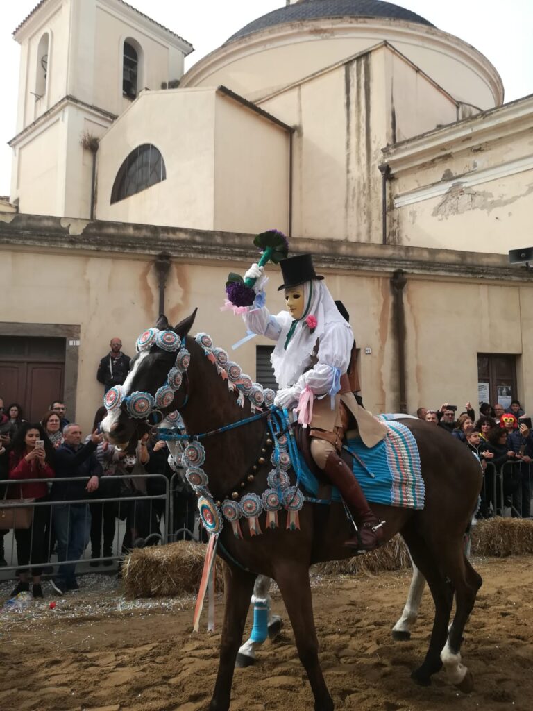 Il capo corsa vestito a festa sopra un cavallo con coccarde rosa e celesti, tiene in mano il mazzo di viole per la benedizione.