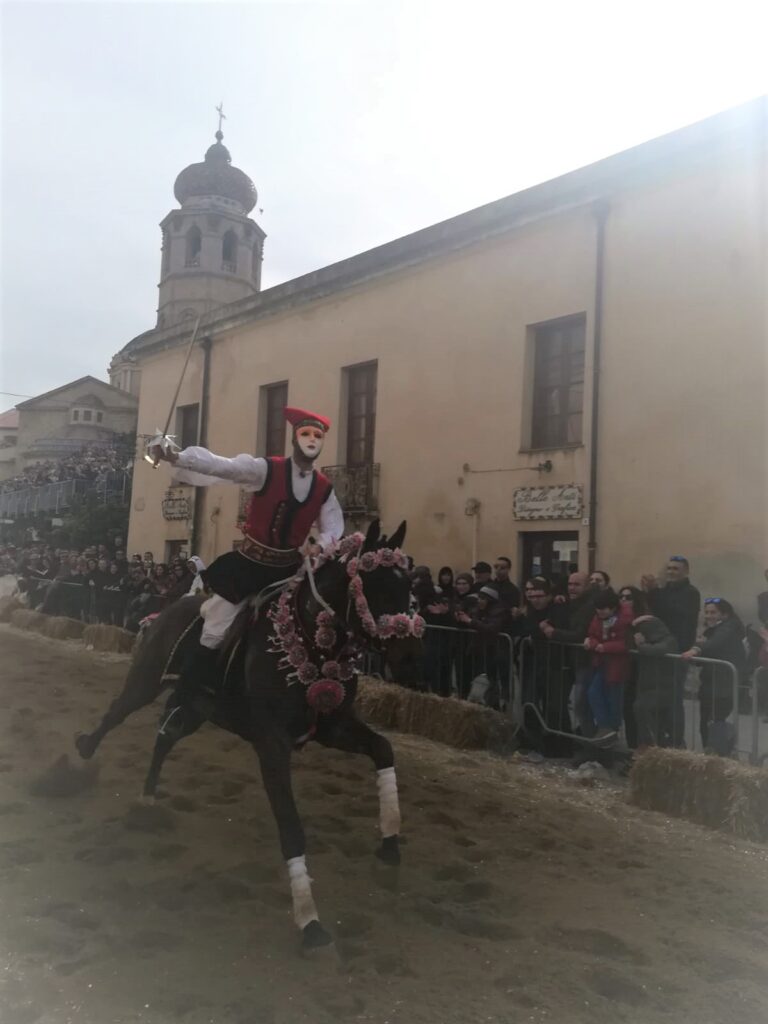Sopra un cavallo con coccarde cavaliere con basco rosso e mascara bicolore, rosa e bianca, che prende la stella.