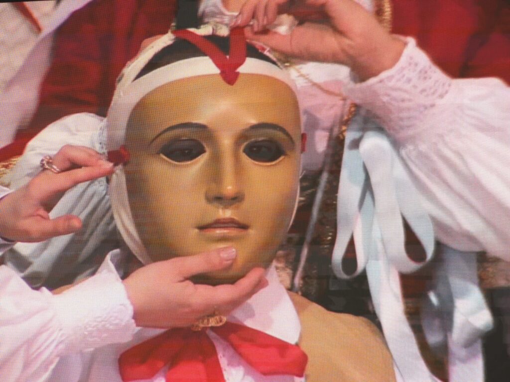 Oristano le massaieddas stanno vestendo su Componidori, al momento gli mettono la maschera color marrone sul viso.