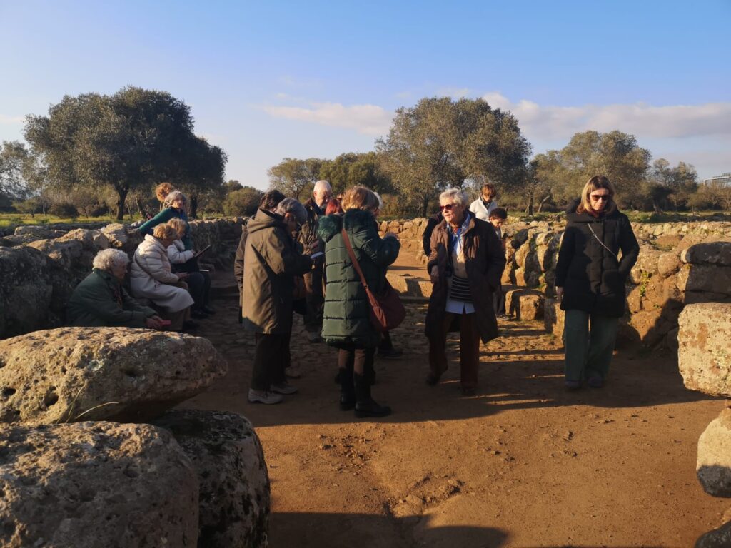 Il gruppo di persone in piedi e seduto dentro due pareti di mura ciclopiche.